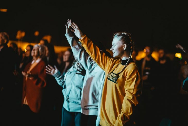 Young woman with her hand up in worship at a Message event