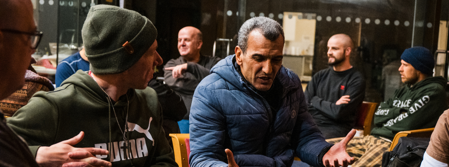 A group of men sit in a circle talking inside a church.