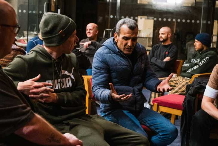 A group of men sit in a circle talking inside a church.