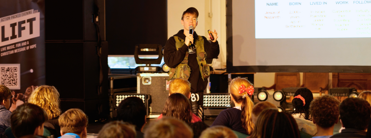 Young man holding a microphone speaks to a group of students
