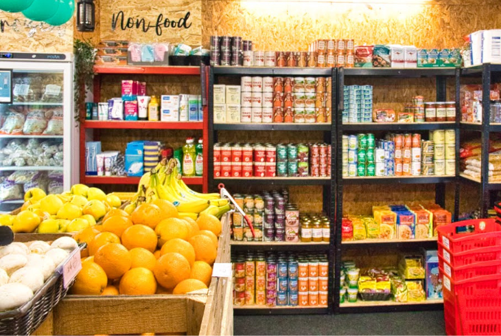 Inside a Community Grocery there's a big fridge, fresh fruit and cupboard items.