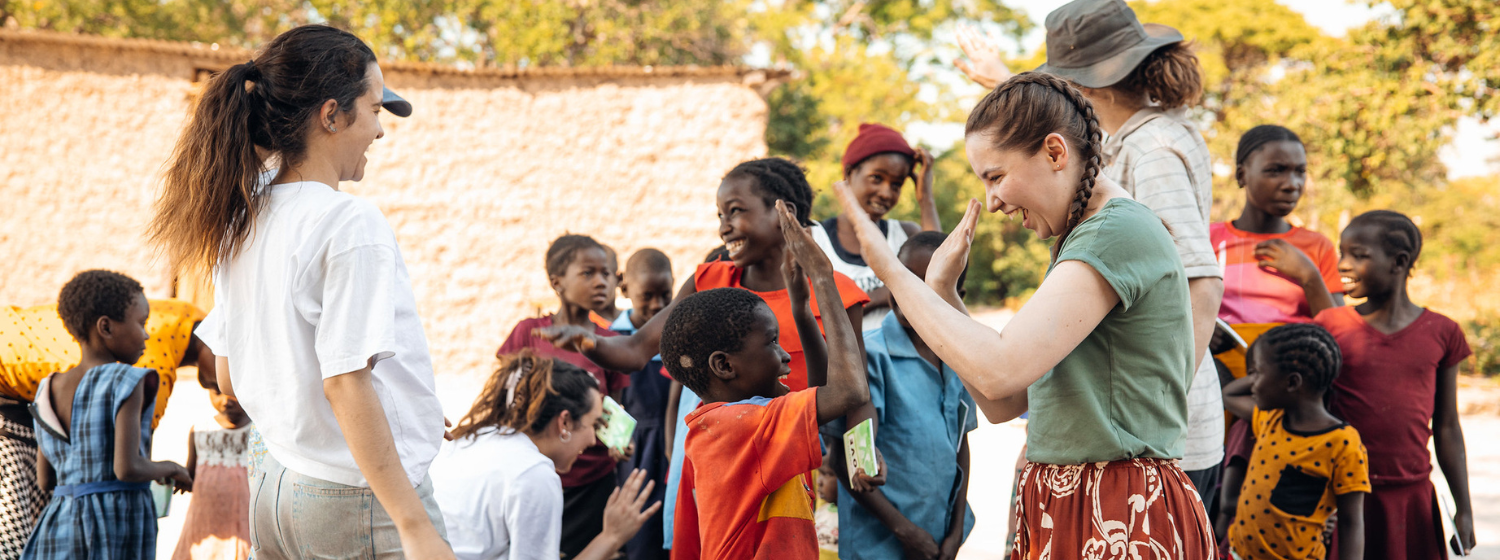A student high fives a child at an outreach event on an international mission trip.