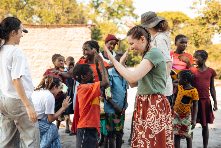 A student high fives a child at an outreach event on an international mission trip.