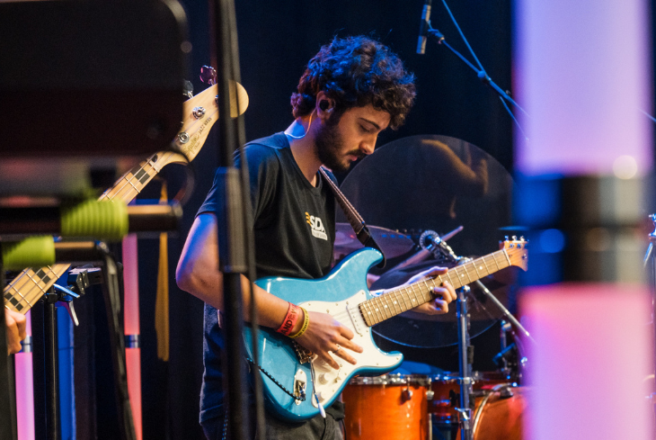 A student plays electric guitar on stage.