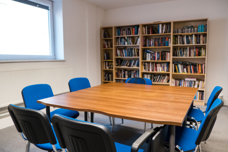 A study room with a table and chairs and bookcases full of books.