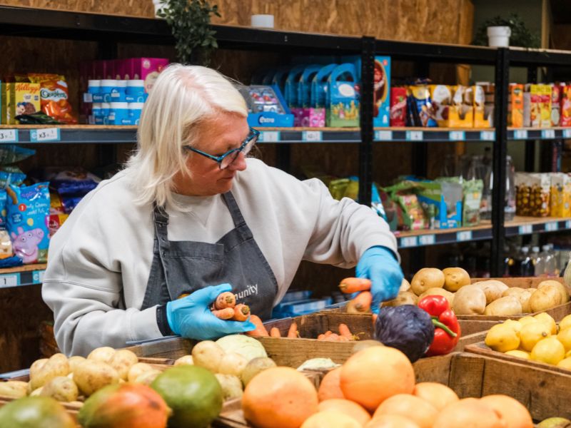 A Grocery volunteer restocks fresh veg.