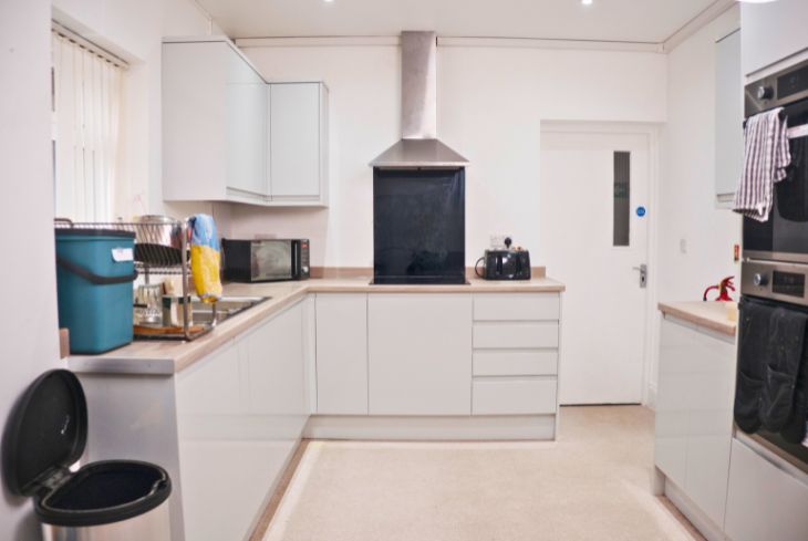 A clean, modern kitchen with white cabinets, a cooker, an oven, a microwave and a toaster.