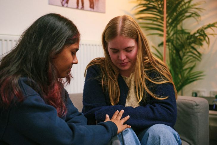 Two women sit and pray together.