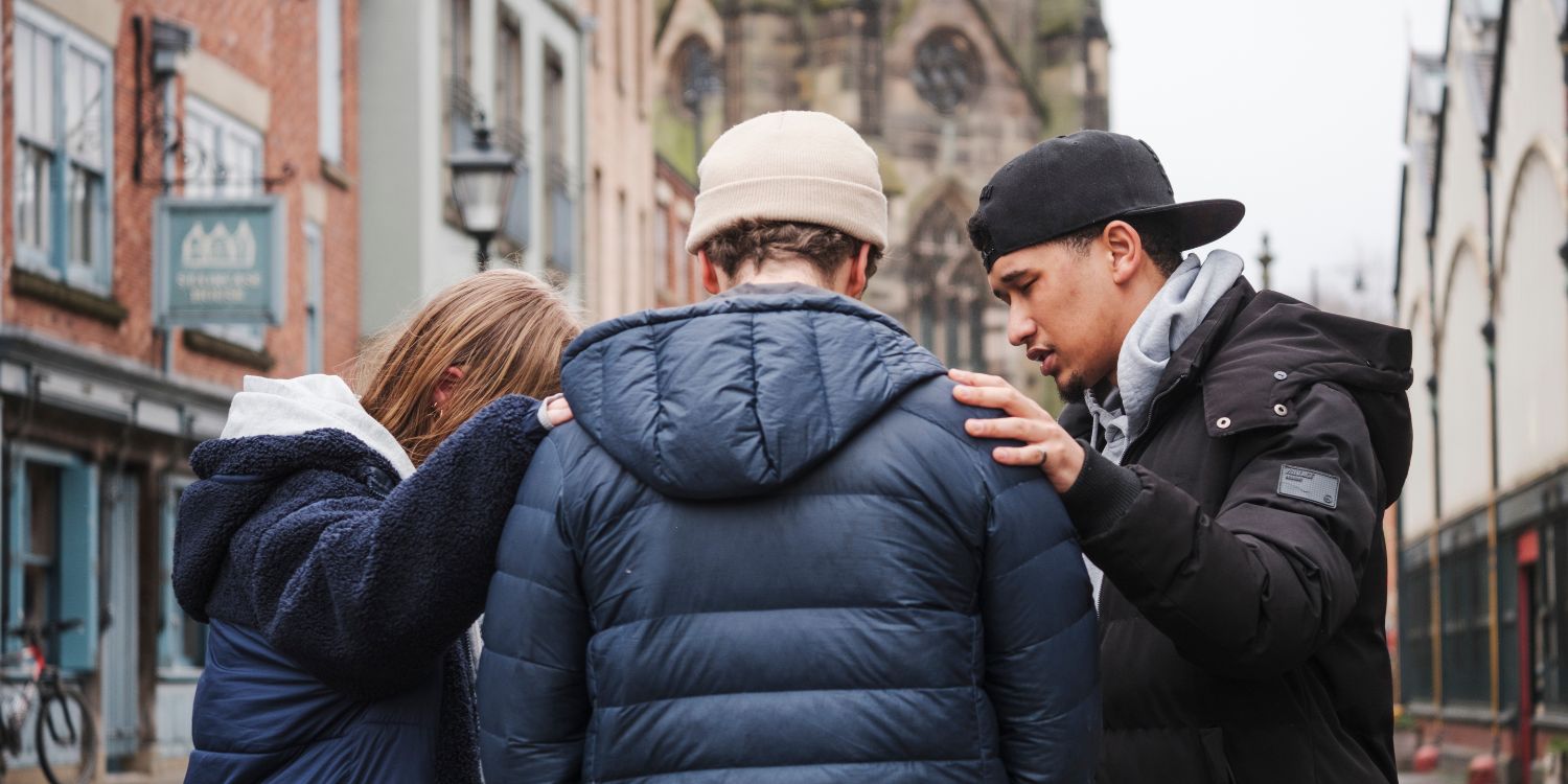 Two MSE students pray for a man on the street.